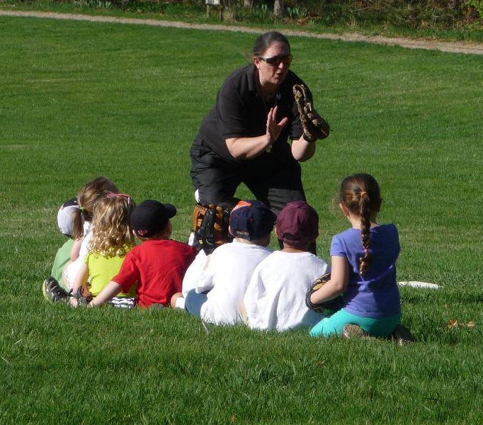 Coach Jo teaches children how to catch a baseball with a glove.