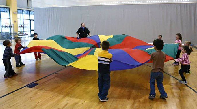 Kids work together to play parachute games. 